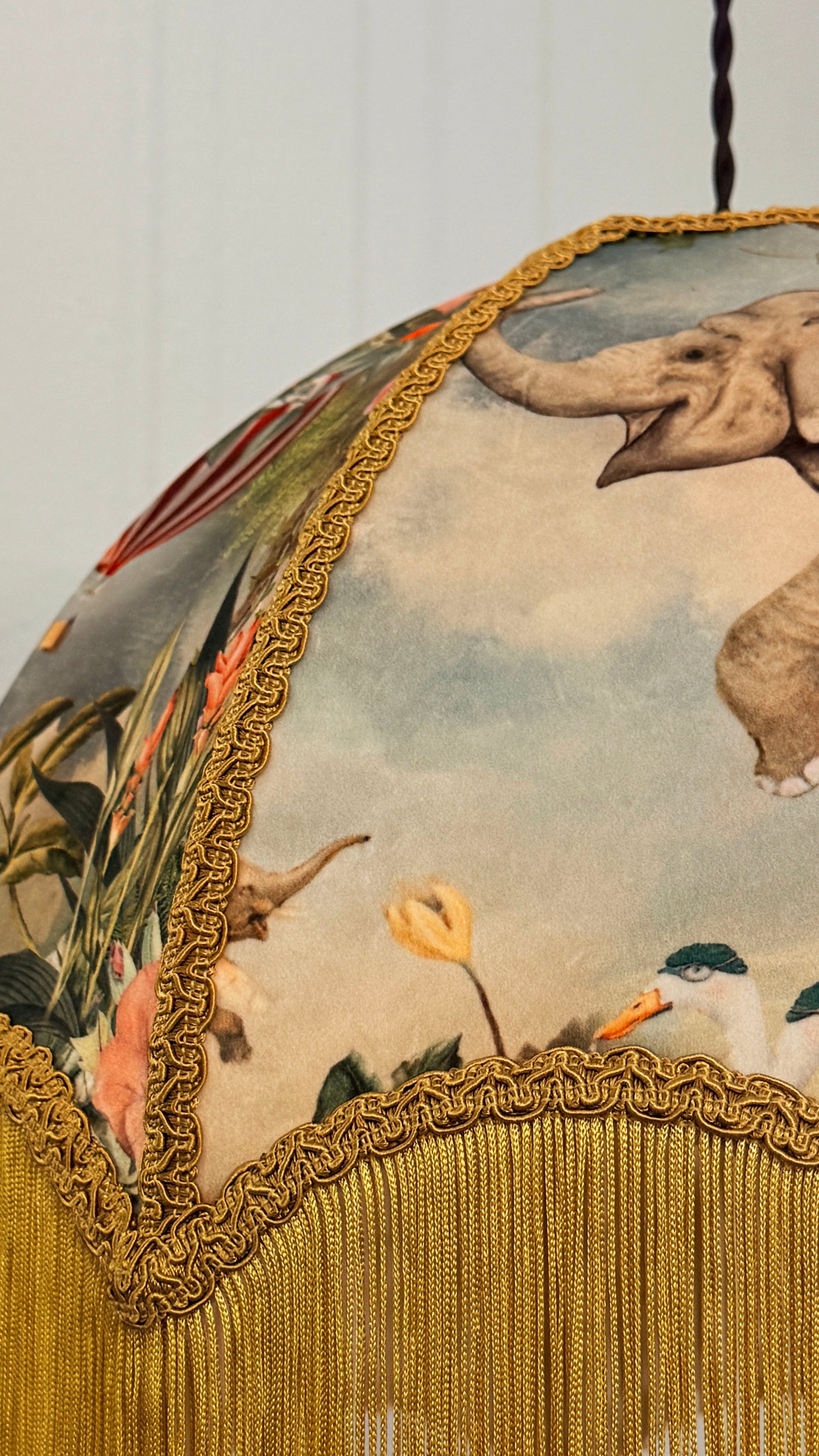 Decorative fabric with elephant and floral design, featuring gold fringe and border.