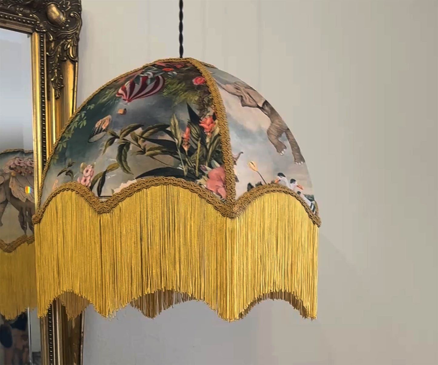 Decorative lampshade with floral design and yellow gold fringe against a neutral background