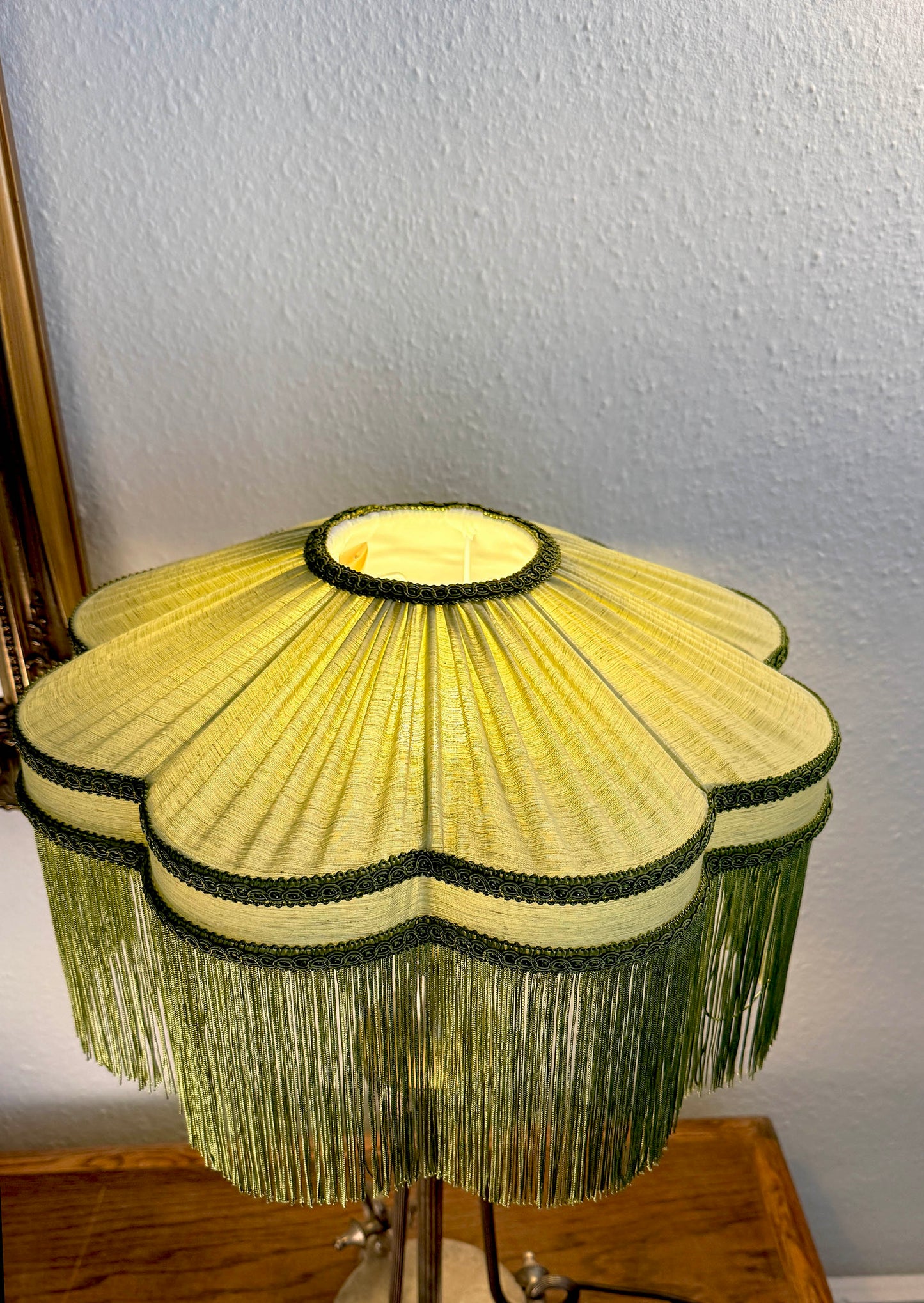 Decorative lamp with a yellow pleated shade on a wooden base against a white wall.