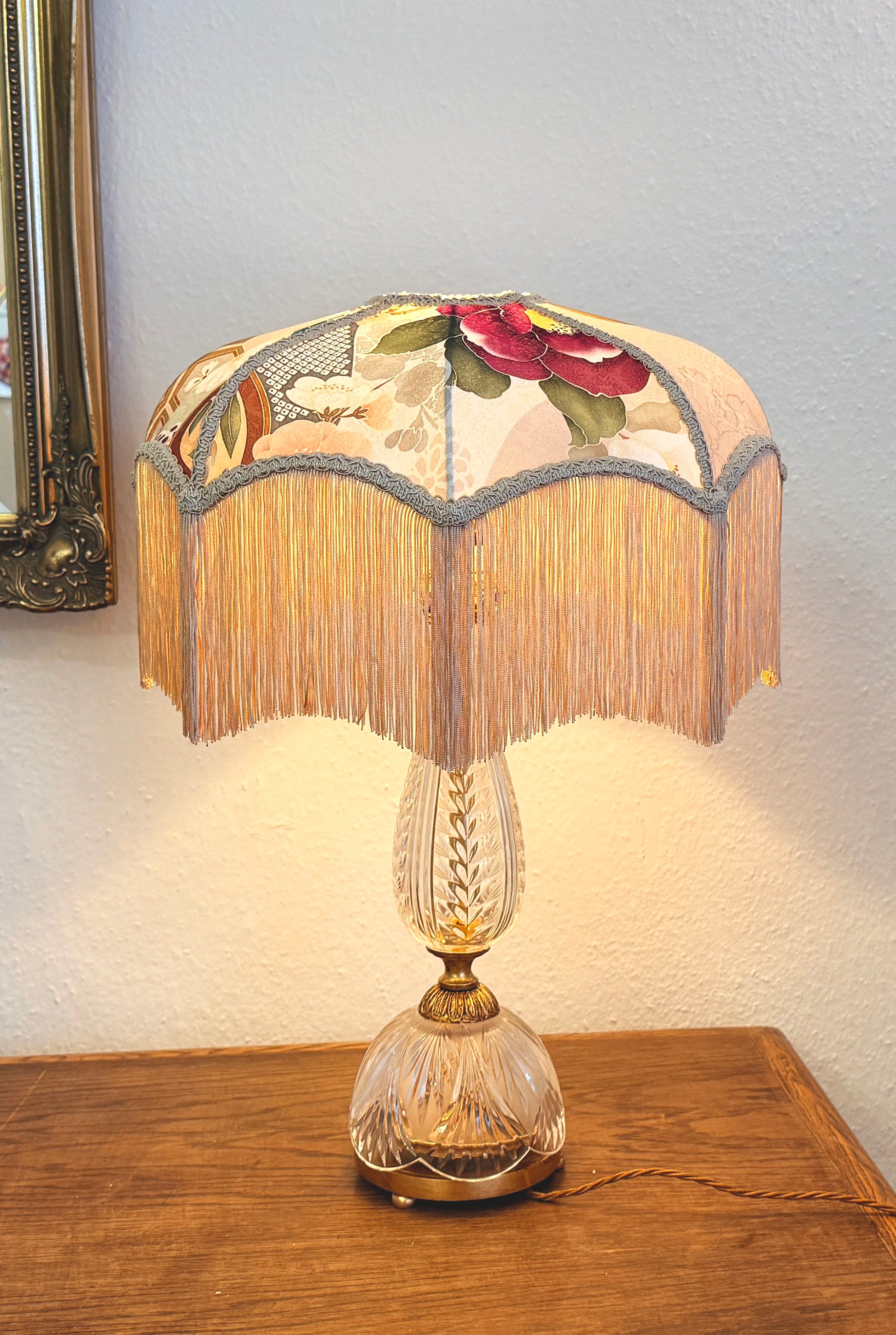 Decorative table lamp with floral lampshade on a wooden surface.