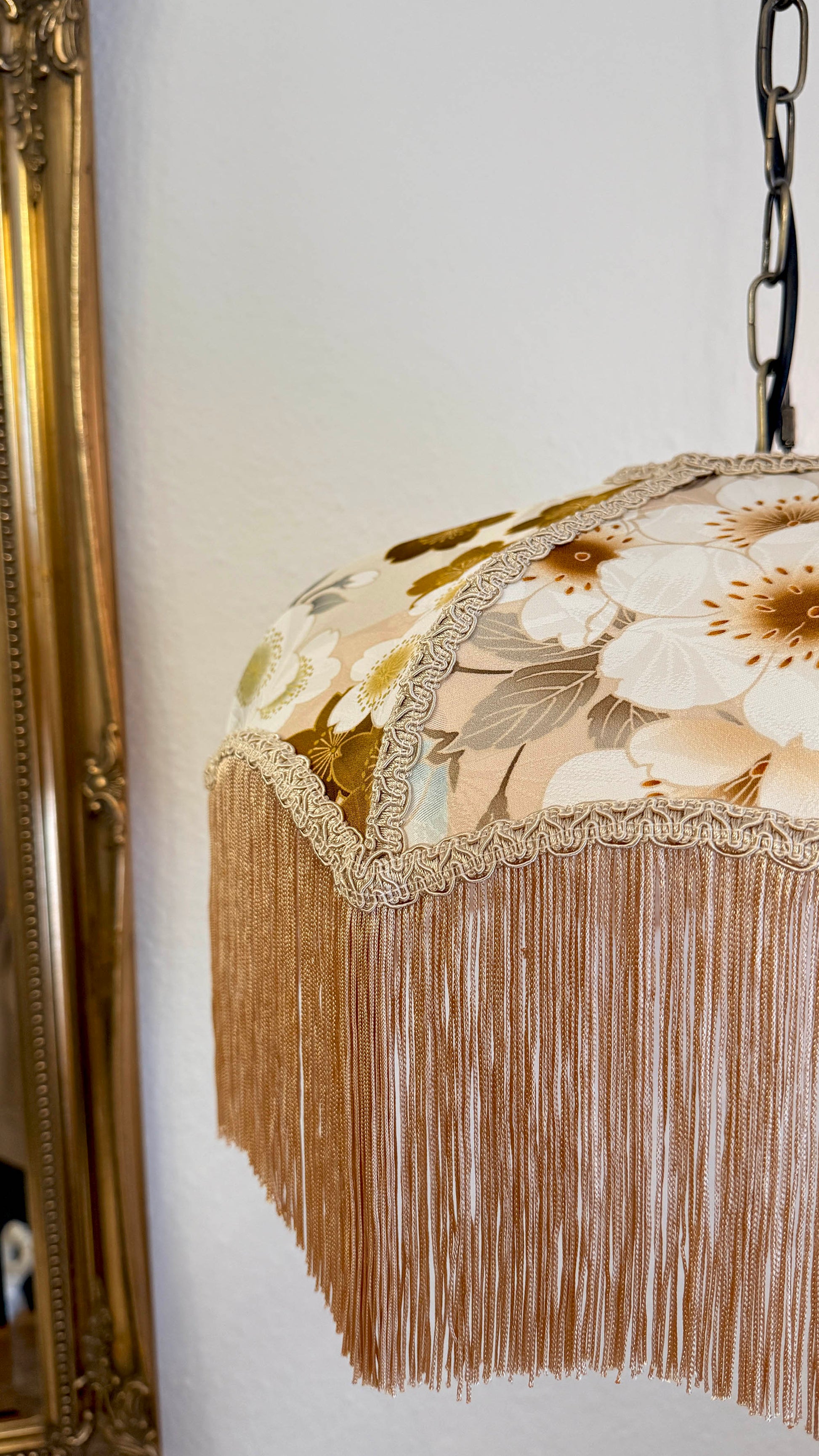 Decorative lampshade with floral pattern and fringe on a white wall. The House of Soft Light