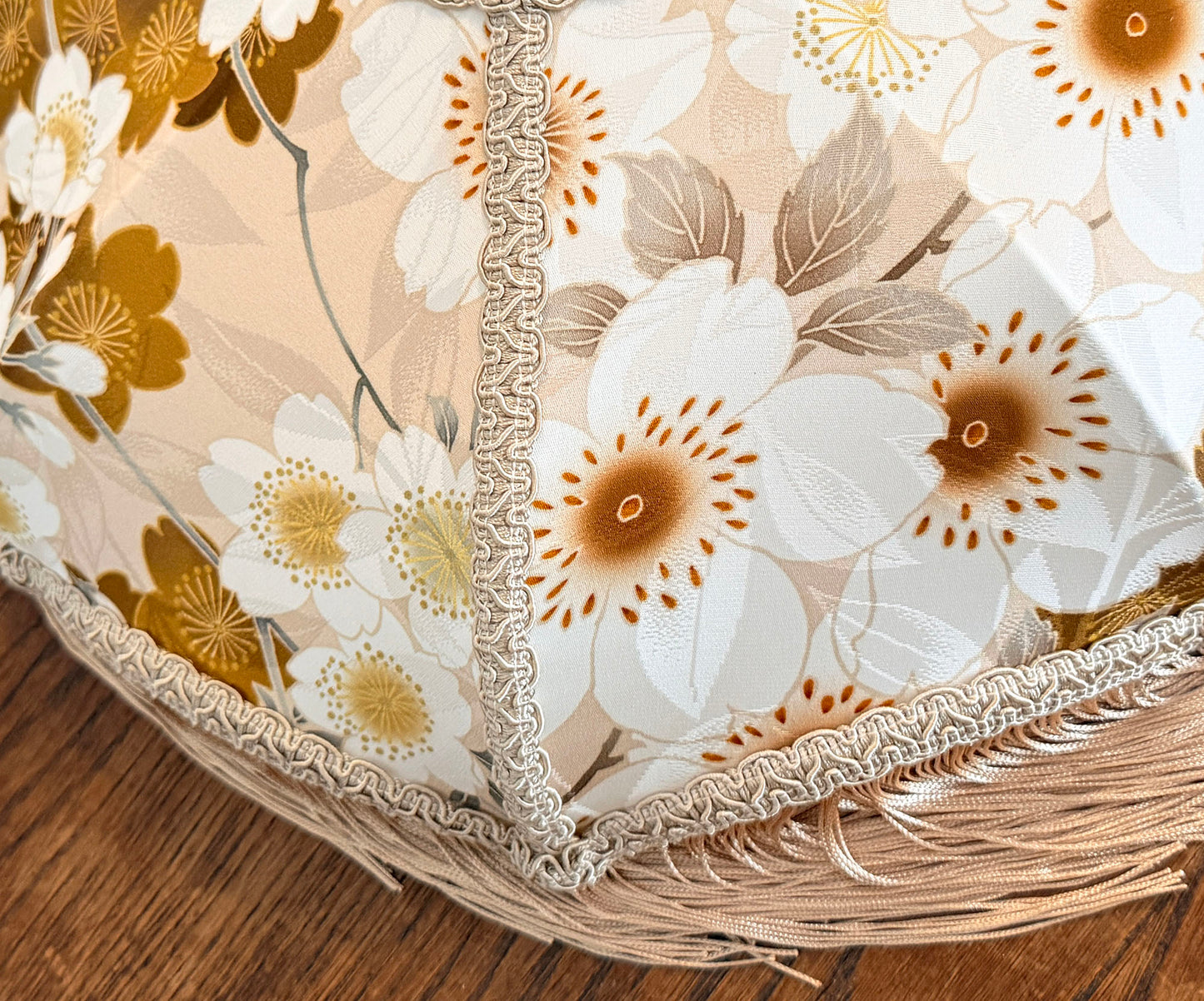 Close-up of a floral-patterned fabric with white and brown flowers lampshade on a wooden surface The House of Soft Light