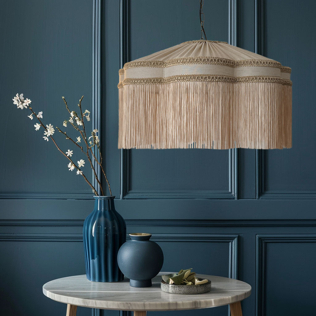 Decorative lampshade hanging above a table with vases and flowers against a dark blue paneled wall. The House of Soft Light