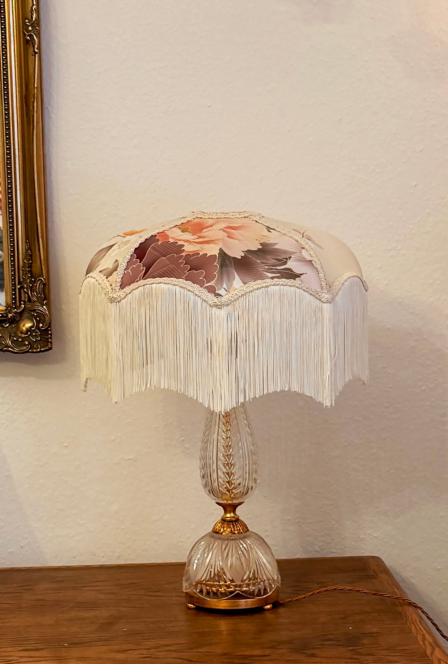 Decorative table lamp with floral shade on a wooden surface.