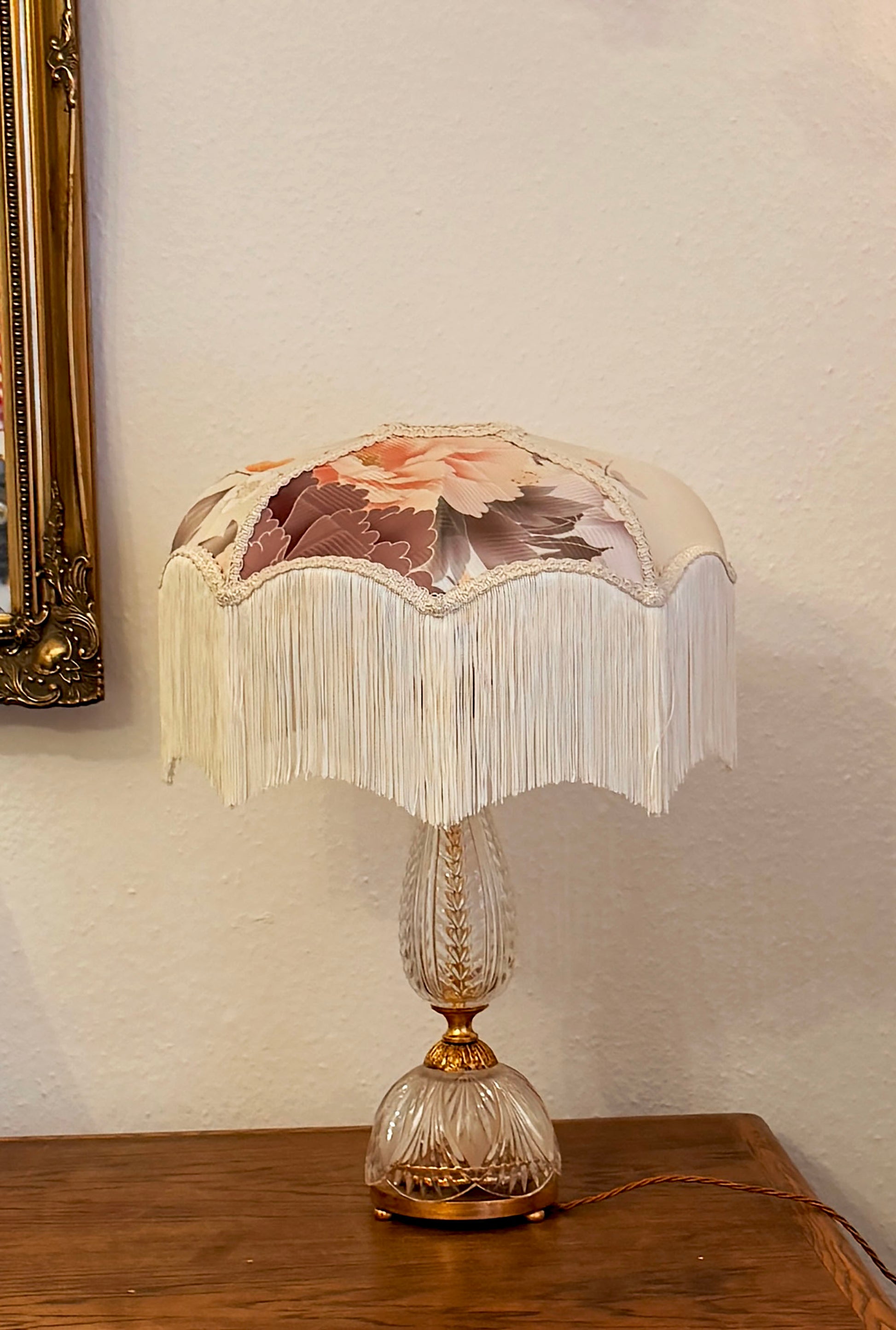 Decorative table lamp with floral shade on a wooden surface.