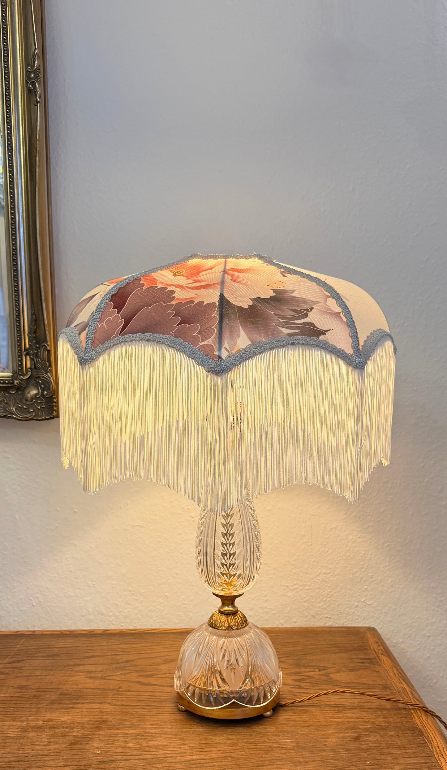 Decorative table lamp with floral lampshade on a wooden surface.