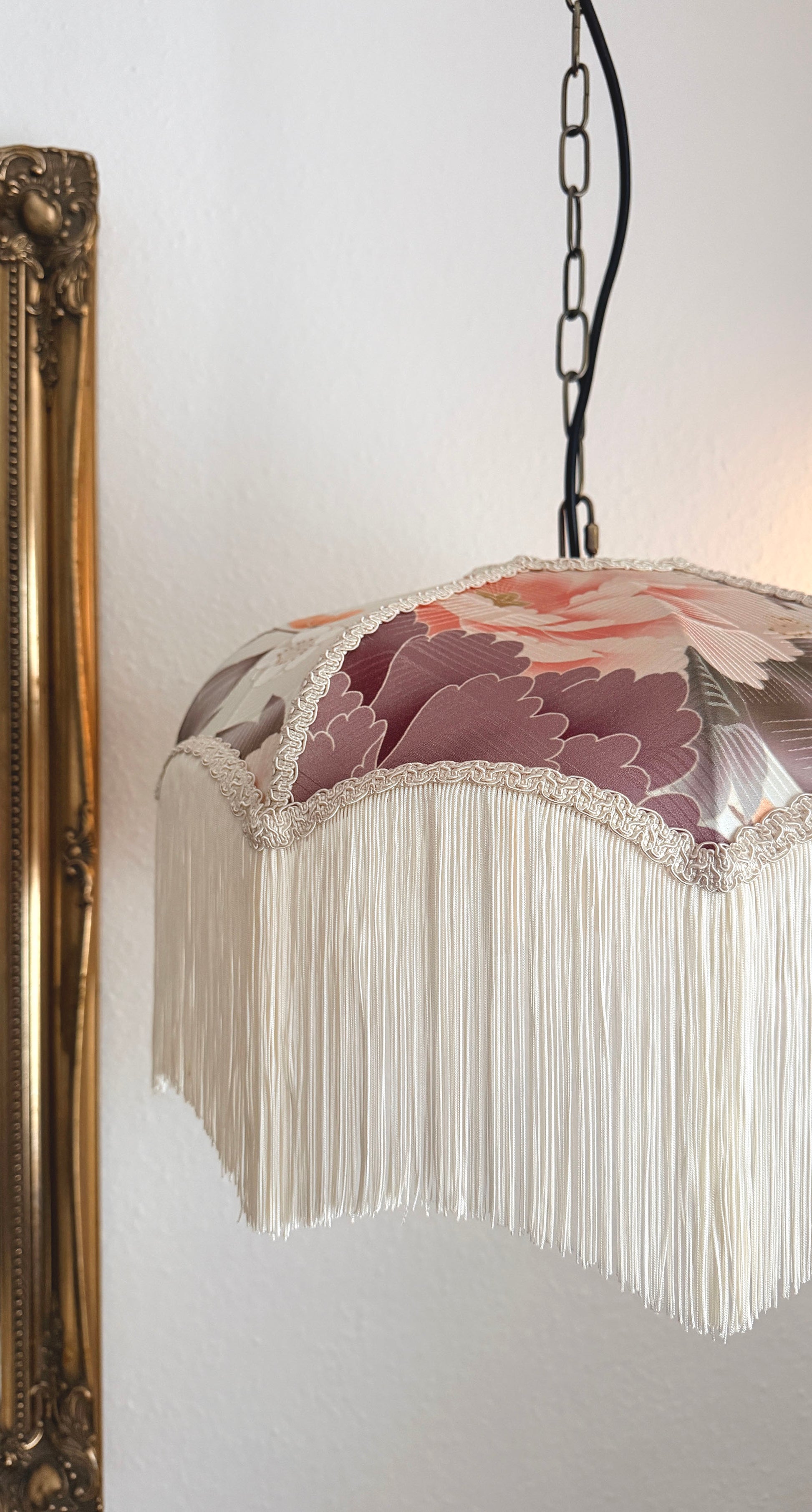 Decorative lamp with floral design and fringe on a white wall. The House of Soft Light