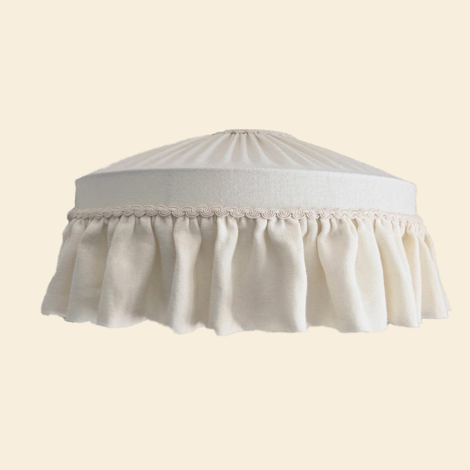 White lampshade with lace trim on a beige background
