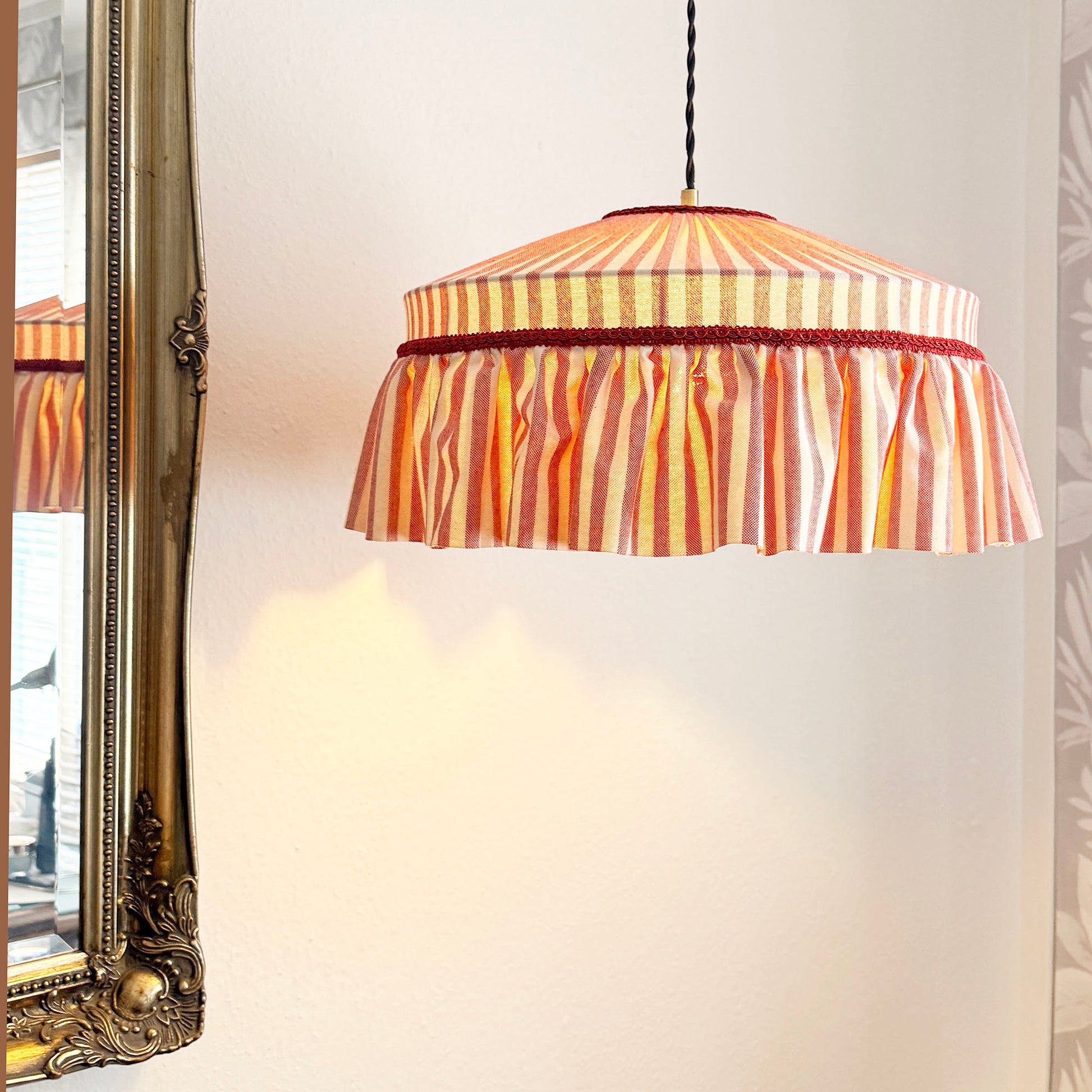 Striped pendant lamp with a decorative frame on a neutral wall.