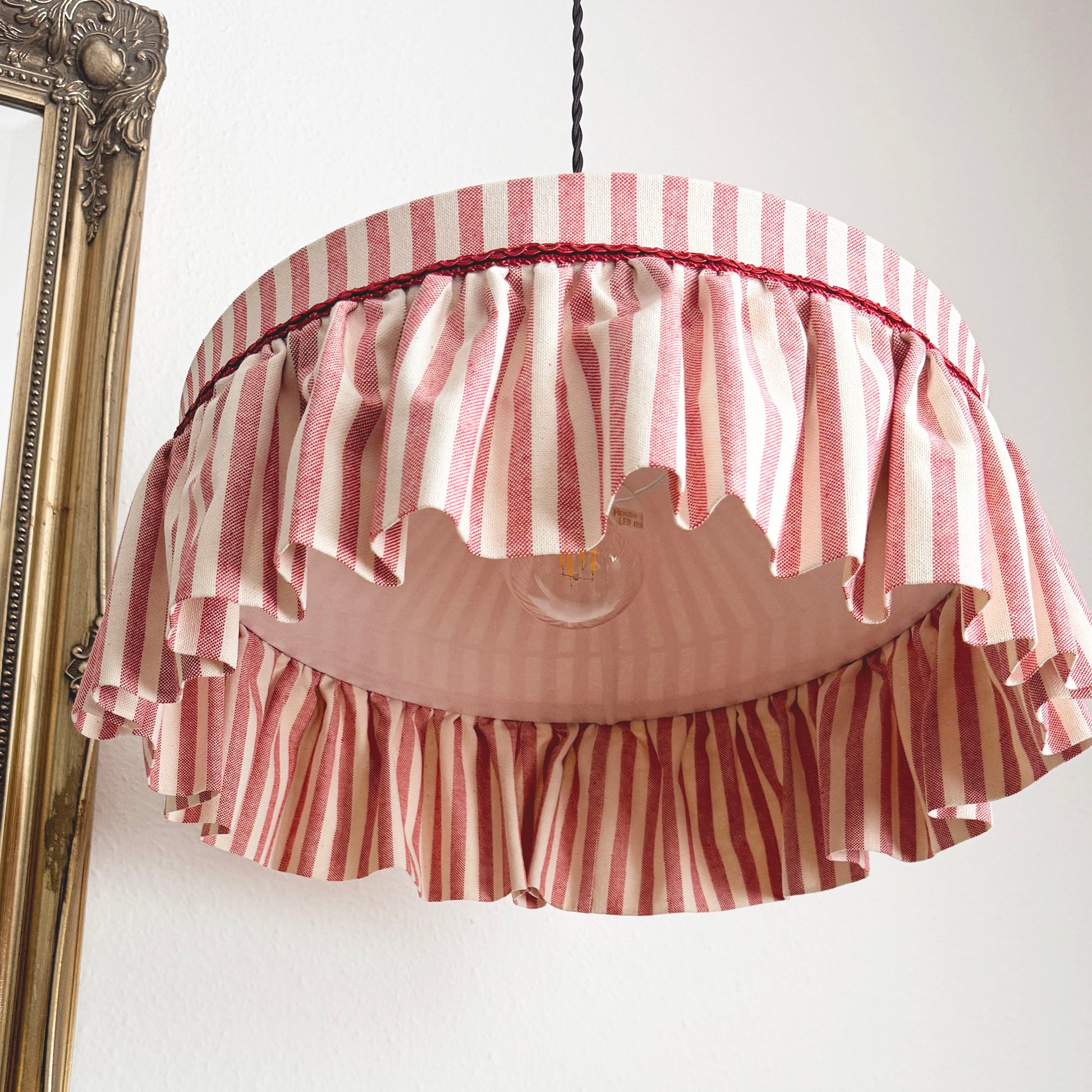 Striped lampshade with ruffles on a white wall