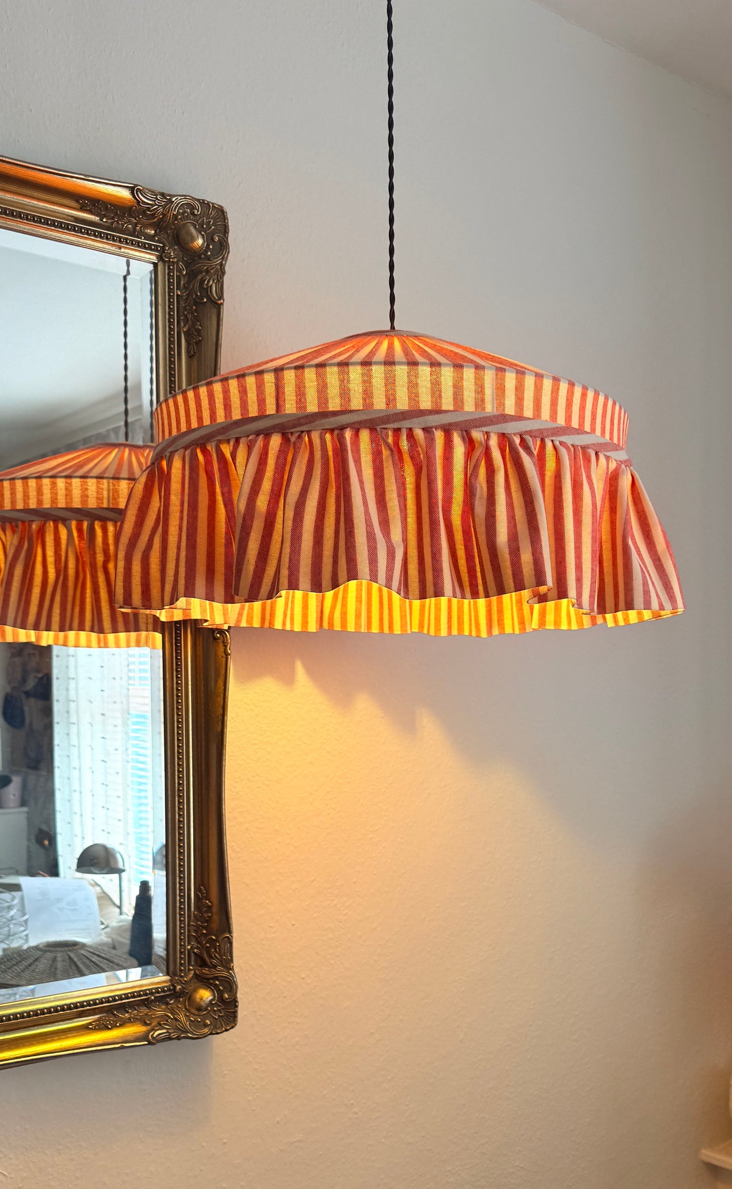 Striped pendant lamp hanging in a room with a decorative mirror.