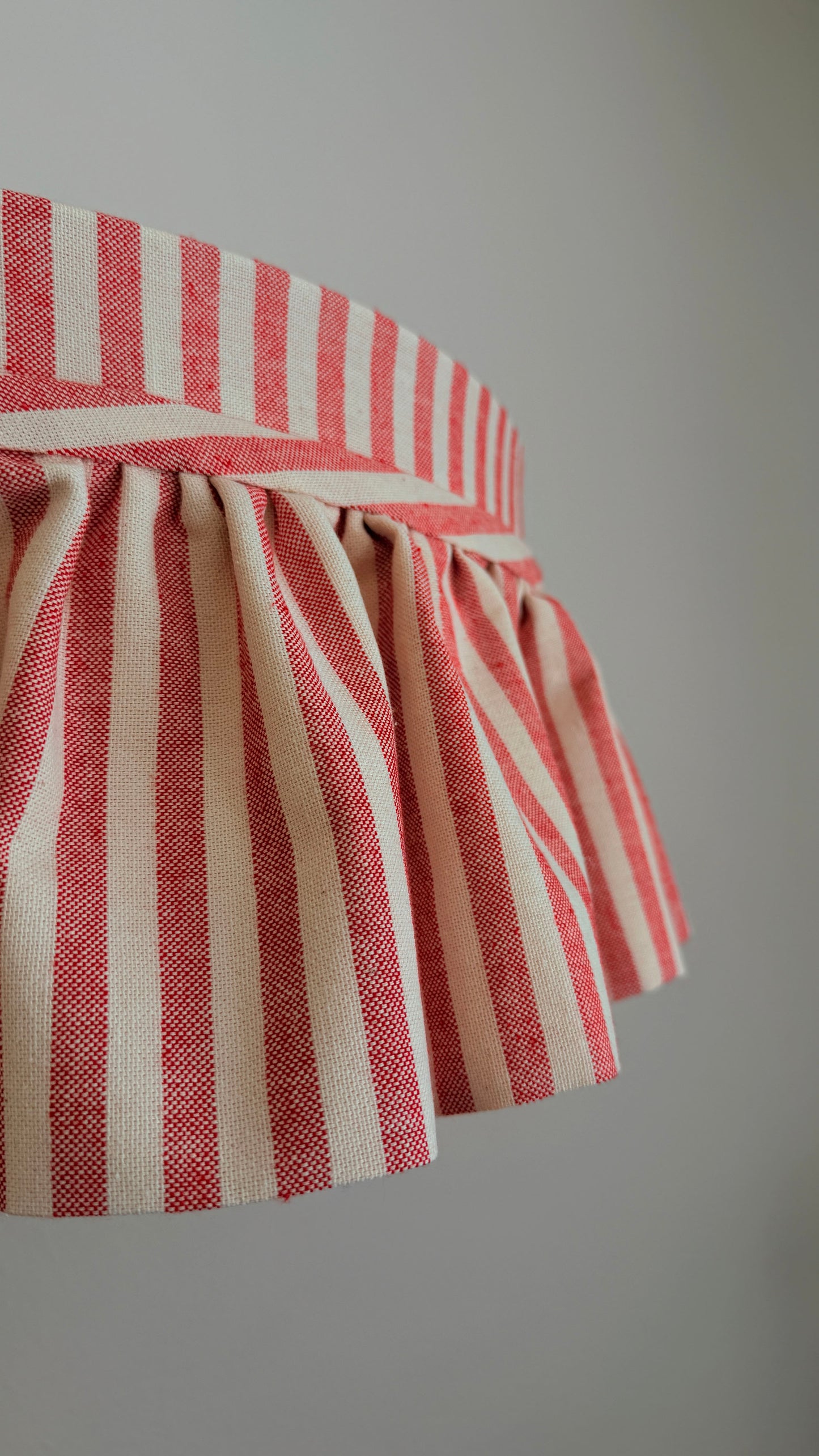 Red and white striped lampshade on a plain background