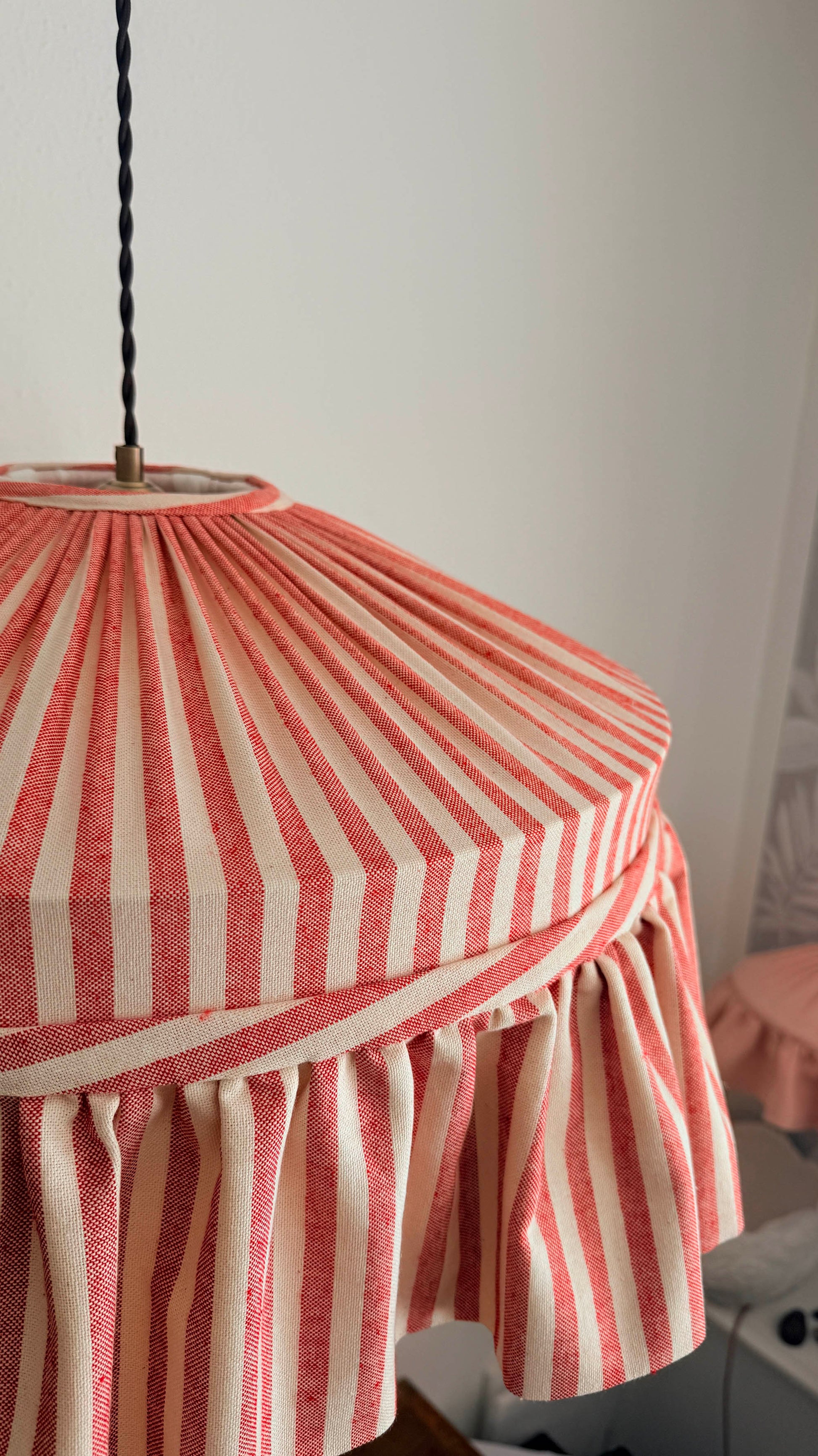 Striped lampshade with red and white pattern on a plain background