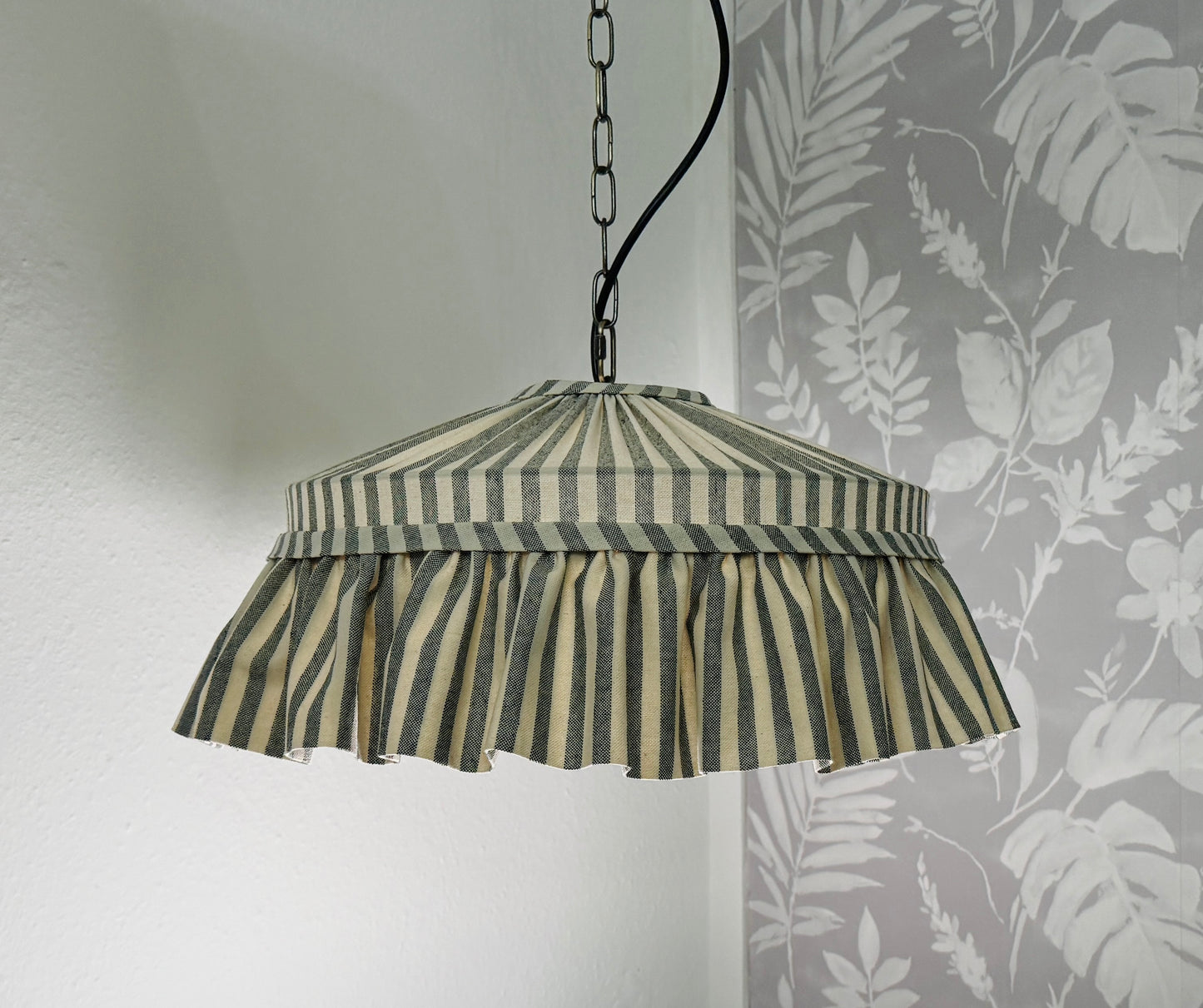 Striped pendant lamp hanging against a wall
