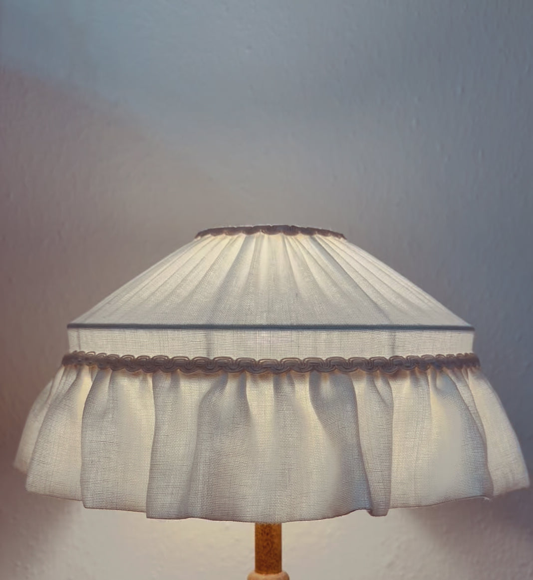 Lamp with a white fabric shade on a plain background