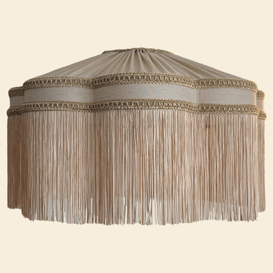 Decorative beige lampshade with fringe on a beige background