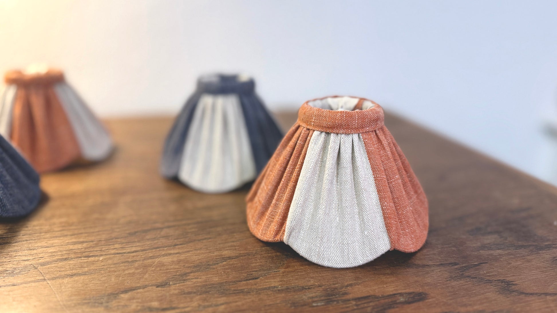 Three linen lampshades on a wooden surface with a blurred background