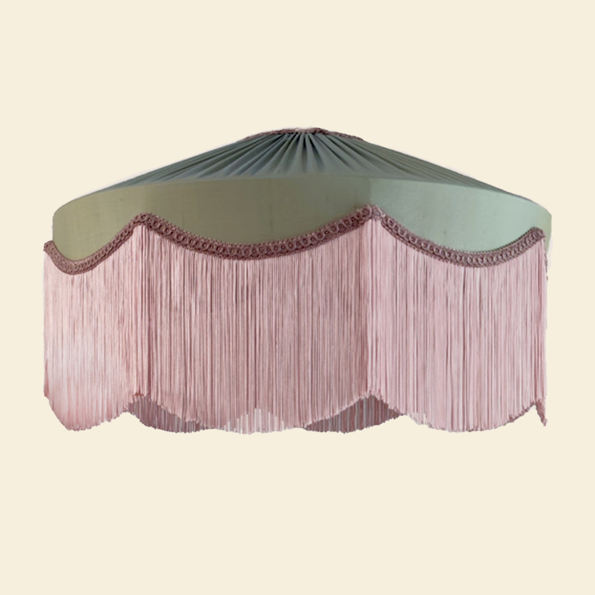 Decorative lampshade with green top and pink fringe skirt on a beige background