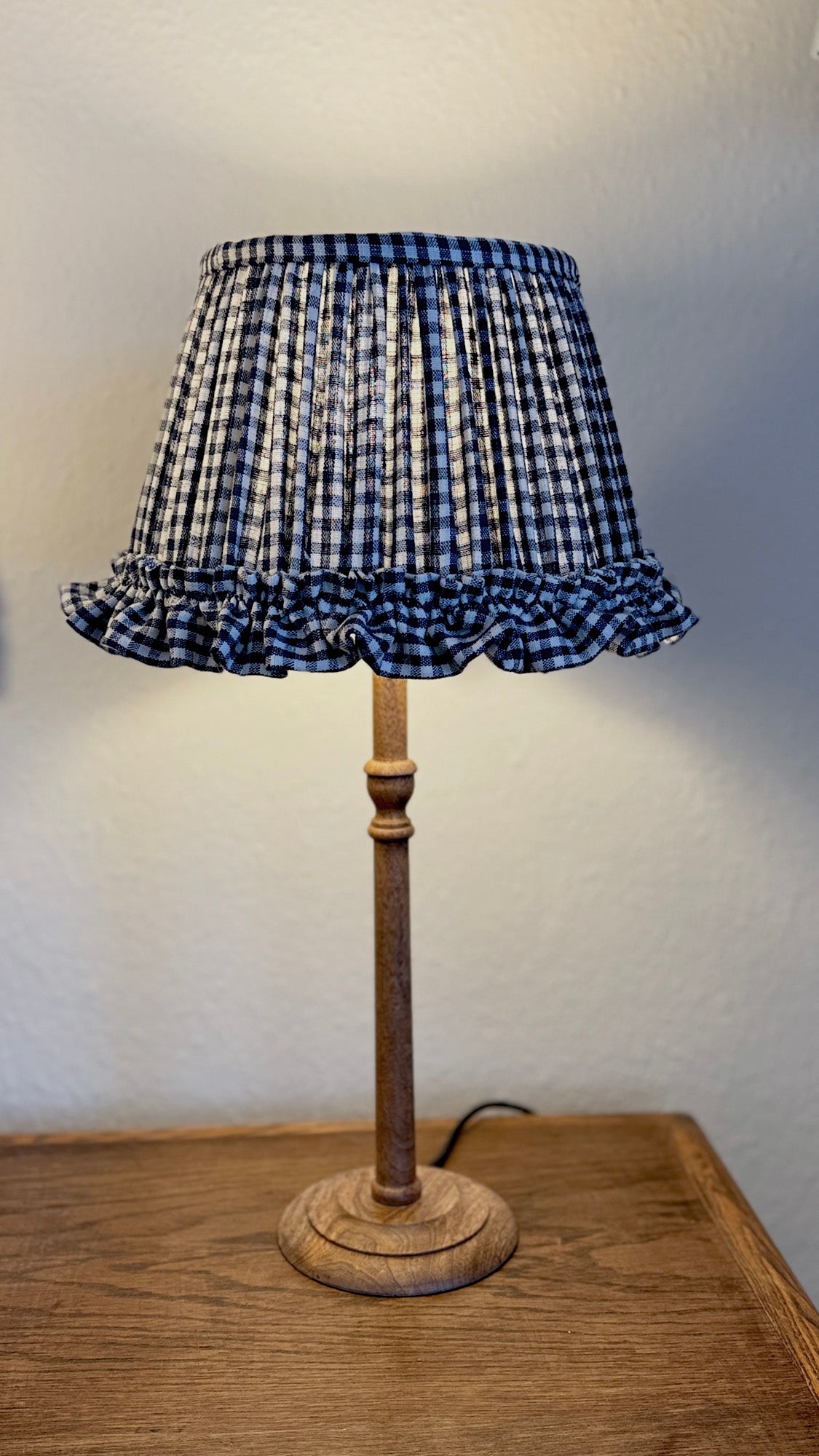 Lamp with a checkered lampshade on a wooden base against a plain background