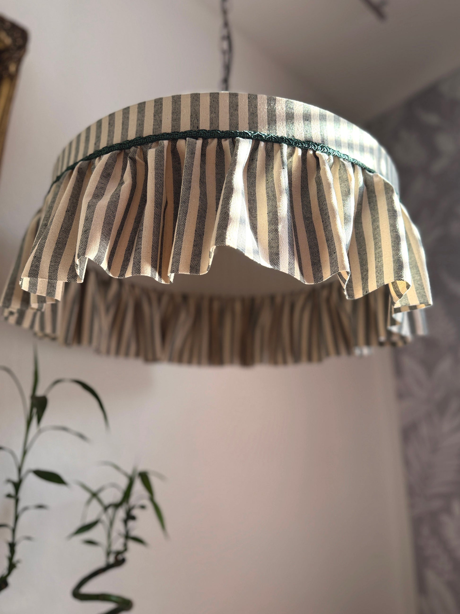 Ruffle green striped cotton lampshade with frilled edge, hanging as a ceiling pendant in a cottage-style interior. Ideal for romantic or country homes.