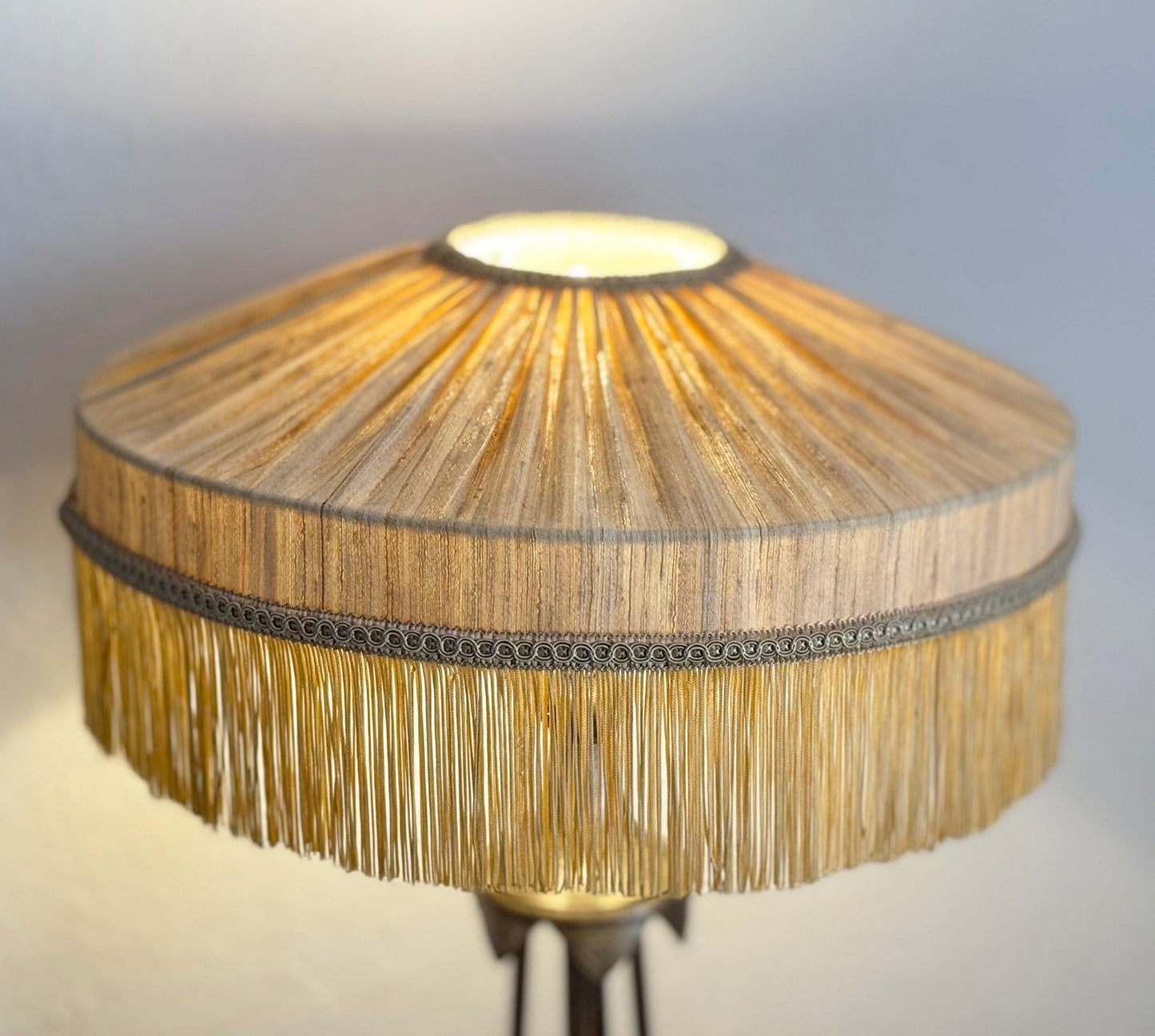 Lamp with a textured shade and fringes on a neutral background
