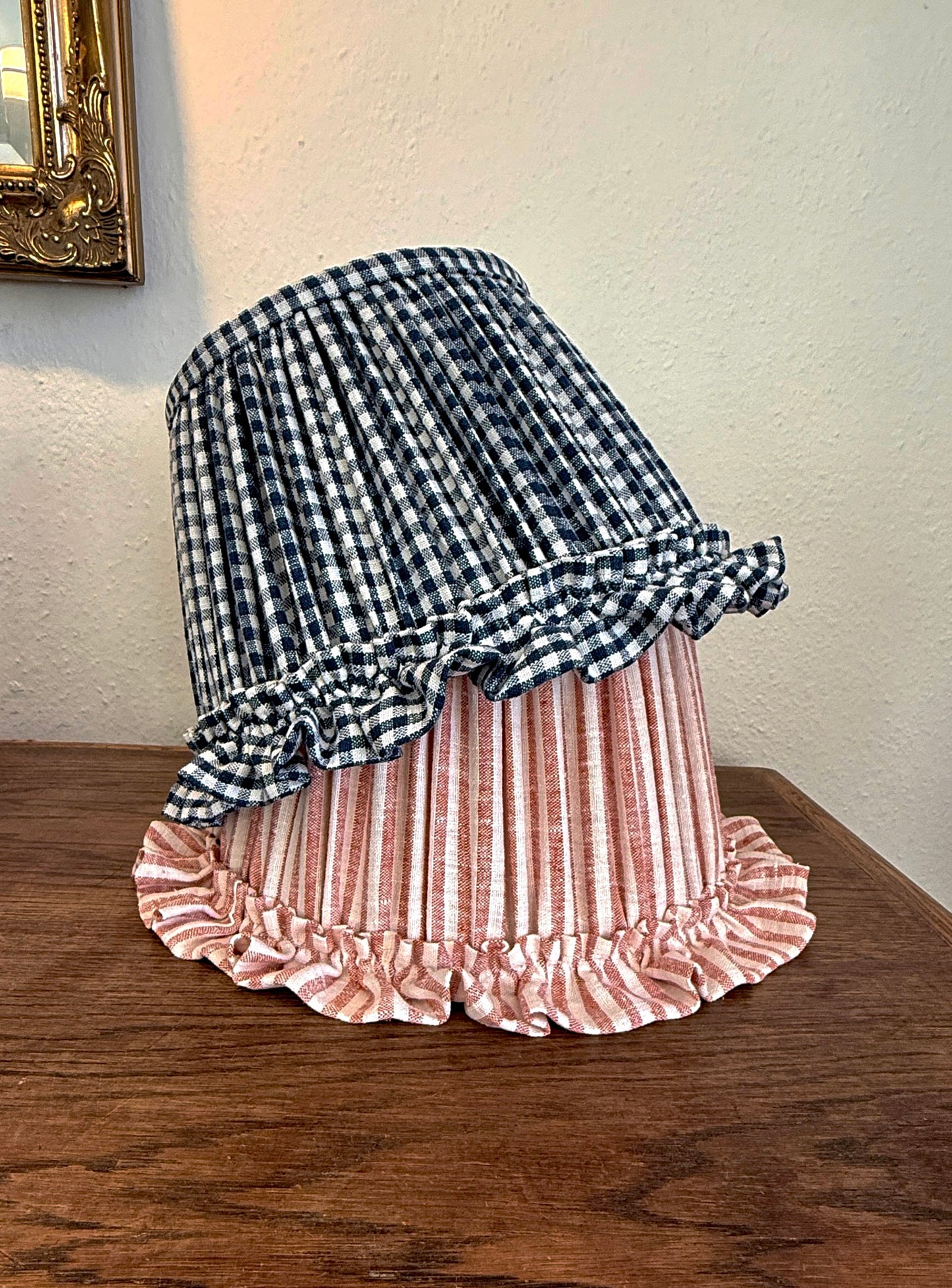 Pair of Striped and Checkered lampshades with ruffled trim on a wooden surface