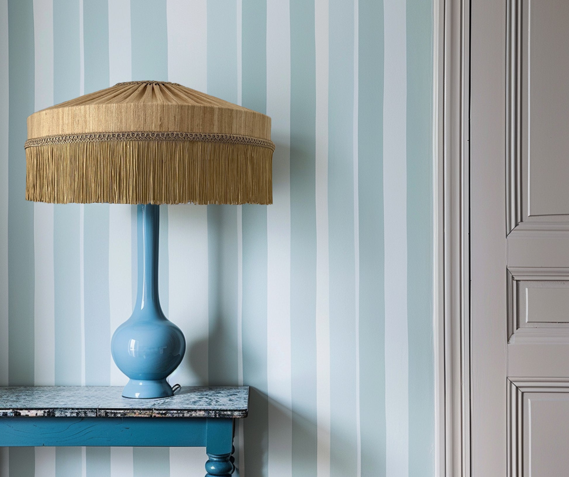 Blue lamp with a wooden shade on a marble surface against a striped wall.