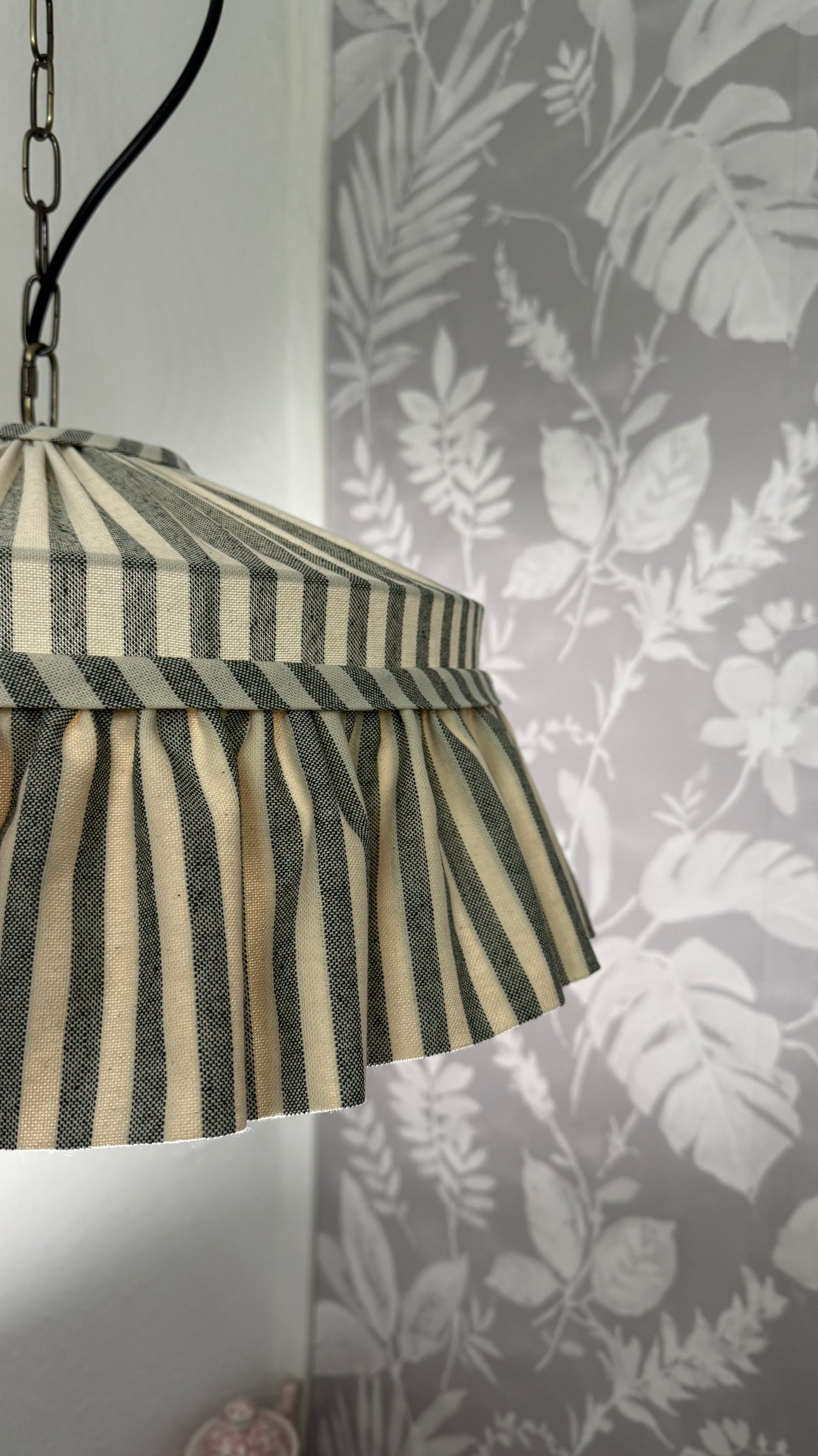 Striped lampshade against a floral wallpaper background